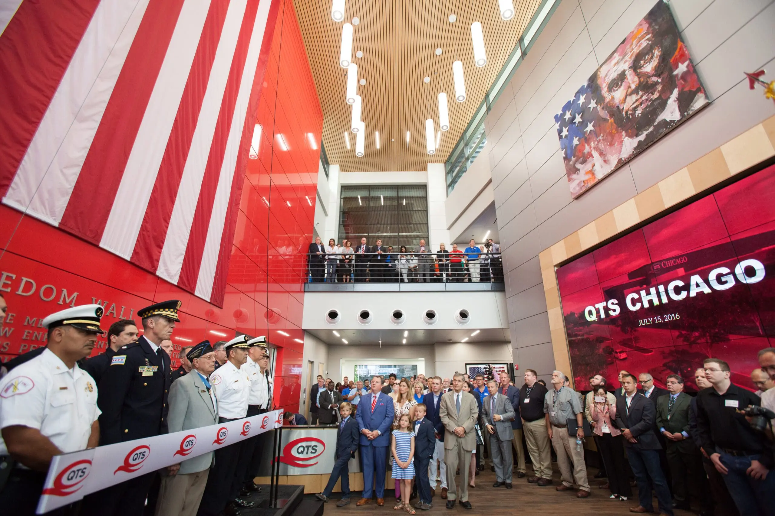 A diverse group of people stands proudly in front of a large American flag at a Chicago event planner.